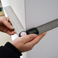 Hands using an Electronic digital display angle ruler against a wall for precise angle and length measurements.